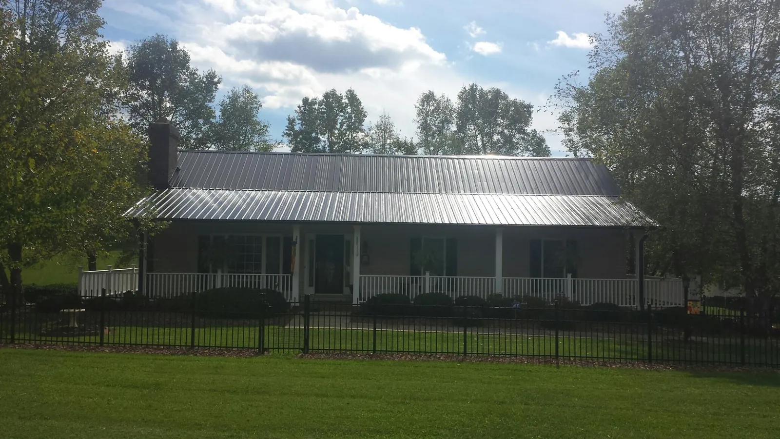 Gray metal roof on a brick ranch with a full width front porch — Gutter Guard Installation work by our crew in Minot