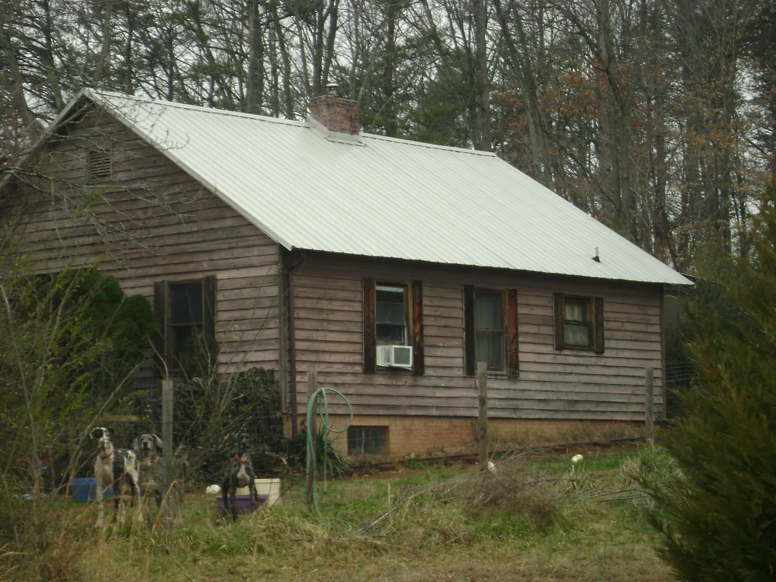 White metal roof on an old wood sided farmhouse, from a Metal Roof Installation job in Minot